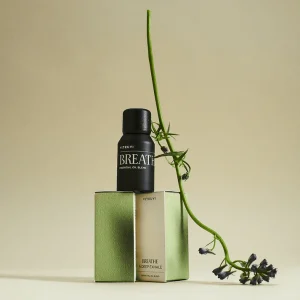 Amber essential oil bottle set on top of green packaging with plant aesthetic