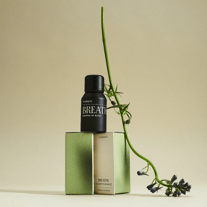 Amber essential oil bottle set on top of green packaging with plant aesthetic