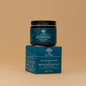 nourishing beard balm by birch babe in packaging against orange backdrop