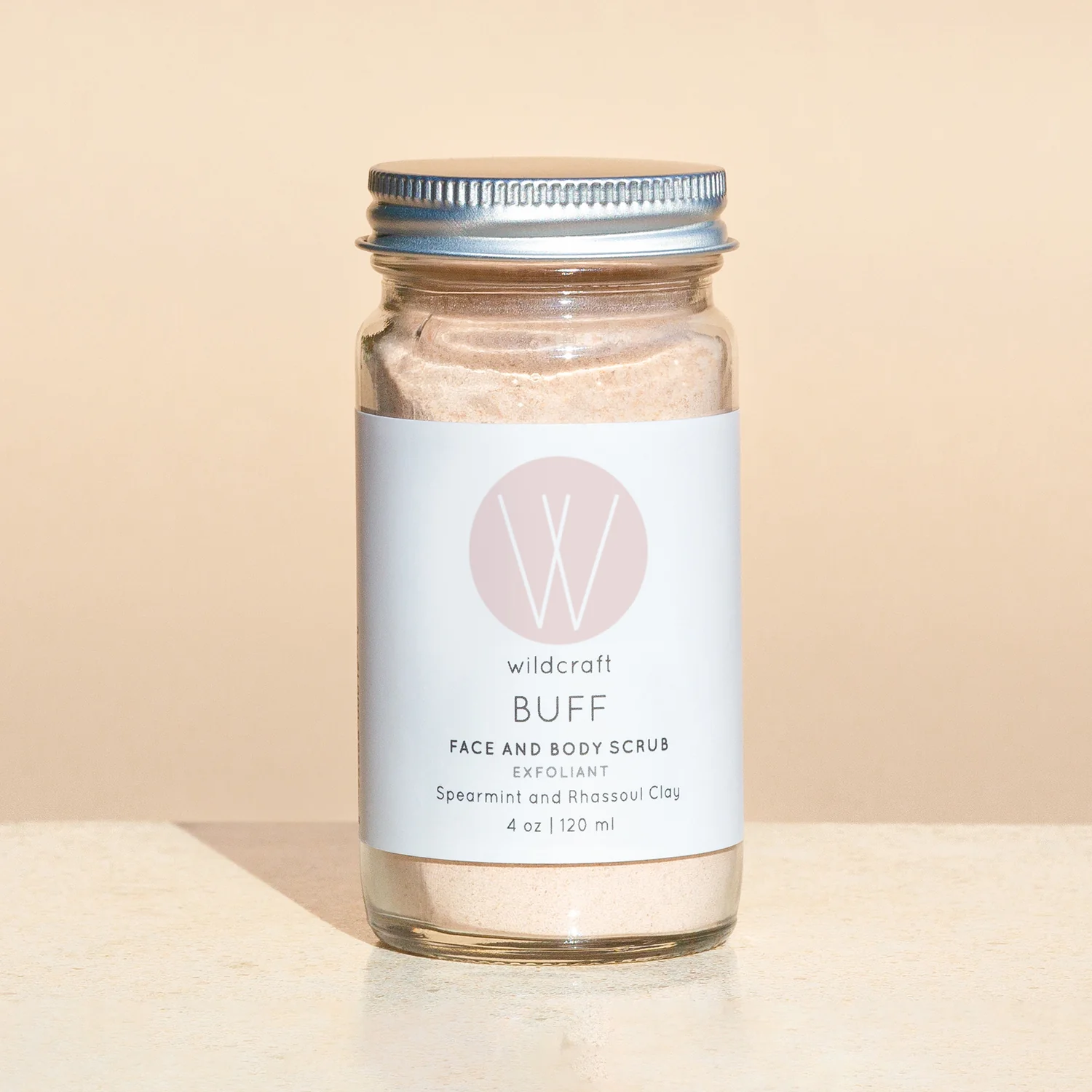 4 oz glass container containing ultra fine pink powder with Wildcraft product label for Buff Face and Body Scrub