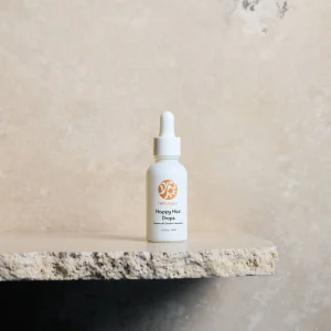 Happy hair drops product photo, white dropper bottle against grey backdrop
